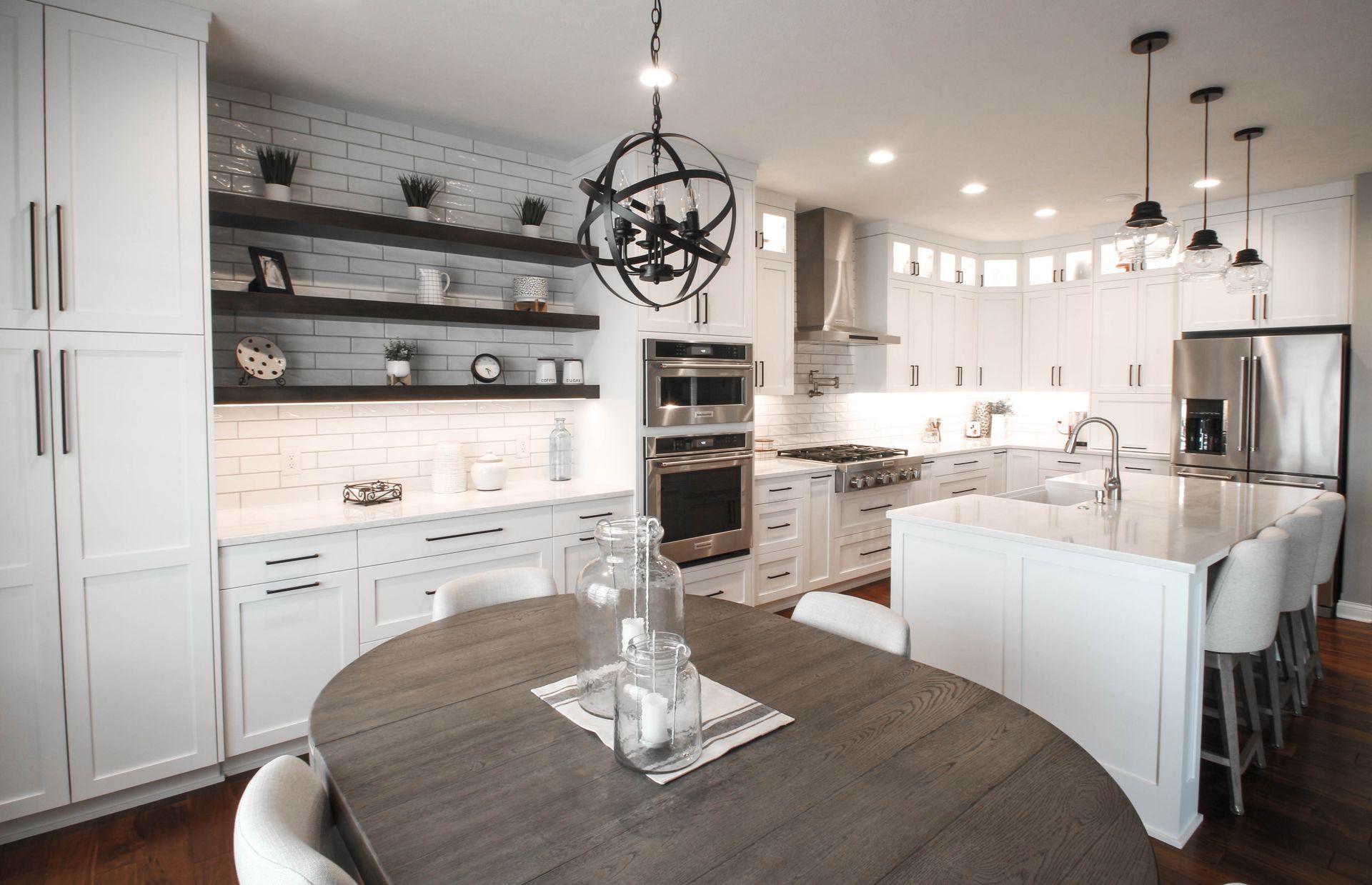 Modern kitchen with white cabinets, island, pendant lights, and stainless steel appliances.