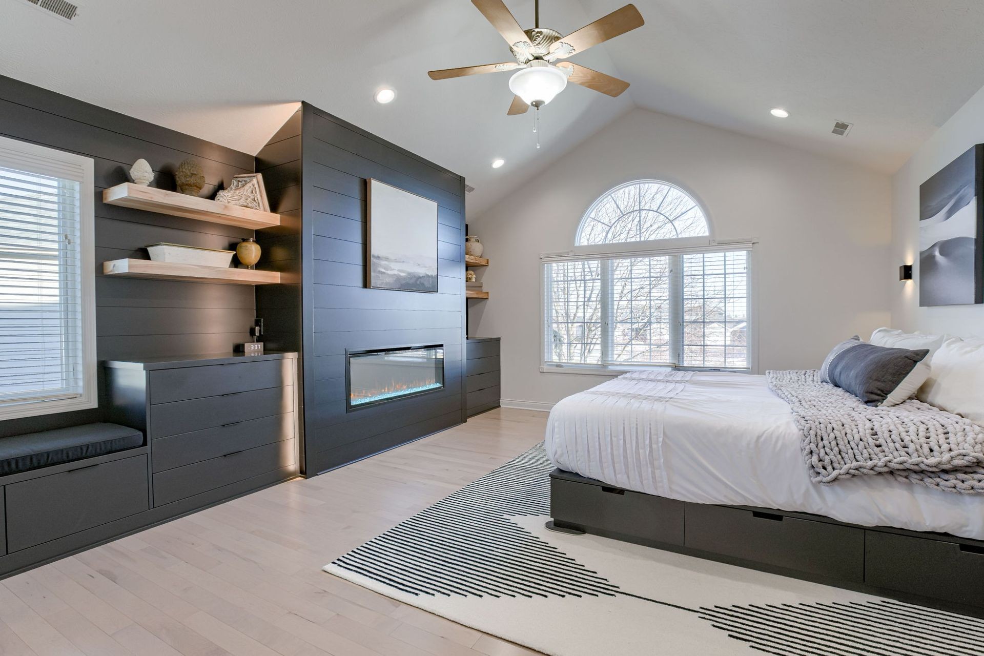 Modern bedroom featuring a fireplace, large windows, and minimalist design elements with neutral colors.